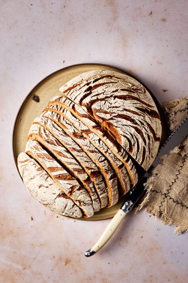 Roggen-Dinkel-Brot mit Sauerteig, aufgeschnitten auf einem Keramikteller.