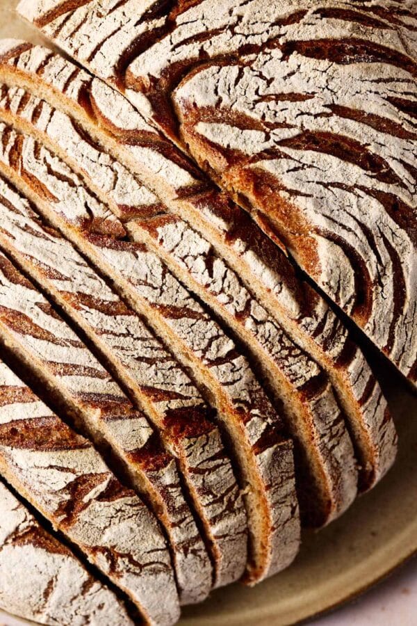 Roggen-Dinkel-Brot mit Sauerteig, aufgeschnitten auf einem Keramikteller.