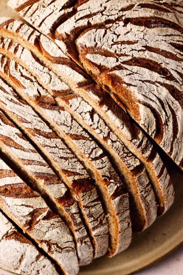 Roggen-Dinkel-Brot mit Sauerteig, aufgeschnitten auf einem Keramikteller.