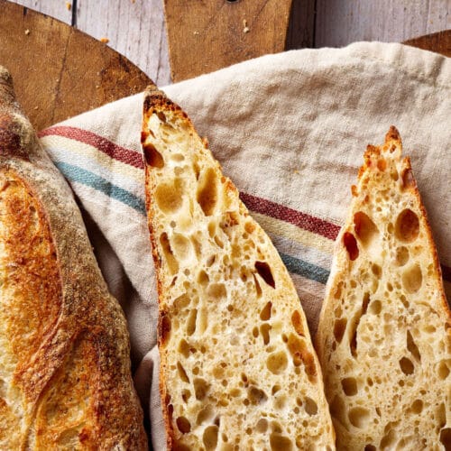 Sauerteig Baguette, aufgeschnitten auf einem rustikalen Holzbrett.