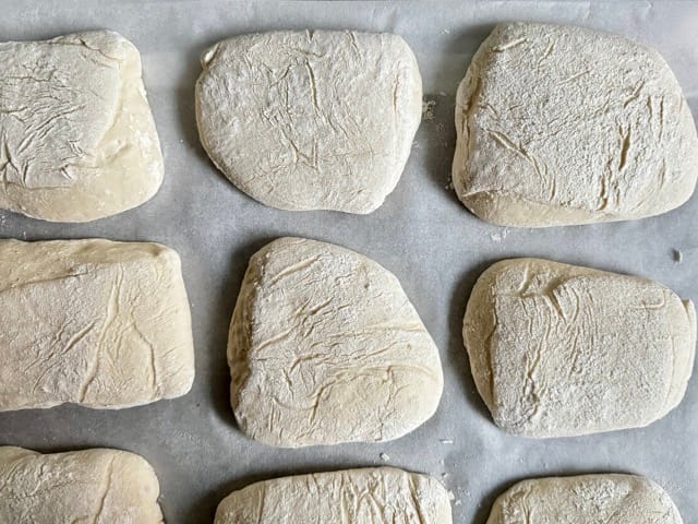 Bröthcen-Teiglinge vor dem Backen, verteilt auf einem Bogen Backpapier auf einem Einschießer.