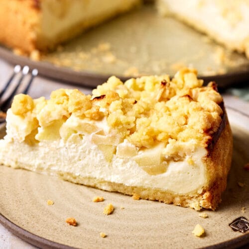 Saftiger Apfelkuchen mit Quark und Streusel auf einem Teller, mit einem Stück Kuchen im Vordergrund.