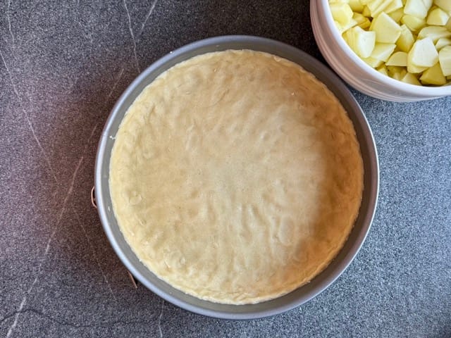 Springform mit Mürbeteig ausgelegt für Apfelkuchen mit Quark und Streusel.