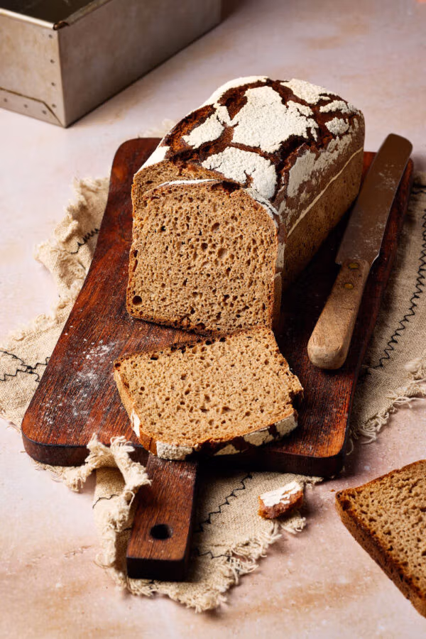Reines Roggenbrot mit Sauerteig aufgeschnitten auf einem rustikalen Holzbrett.