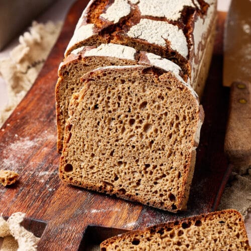 Reines Roggenbrot mit Sauerteig aufgeschnitten auf einem rustikalen Holzbrett.