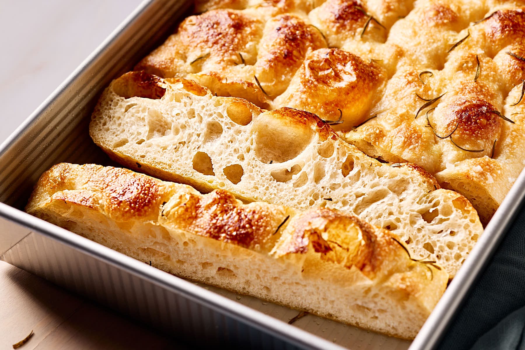 Luftige, angeschnittene Focaccia mit Sauerteig in eine Backform.