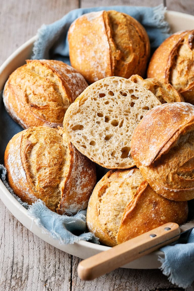 Dinkelbrötchen mit Sauerteig in einer Keramikschale, mit einem Tuch darunter und einem Messer daneben.