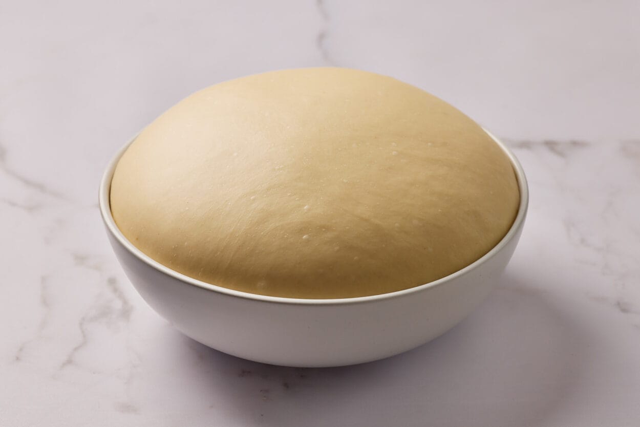 Aufgegangener Hefeteig in einer Keramikschüssel.