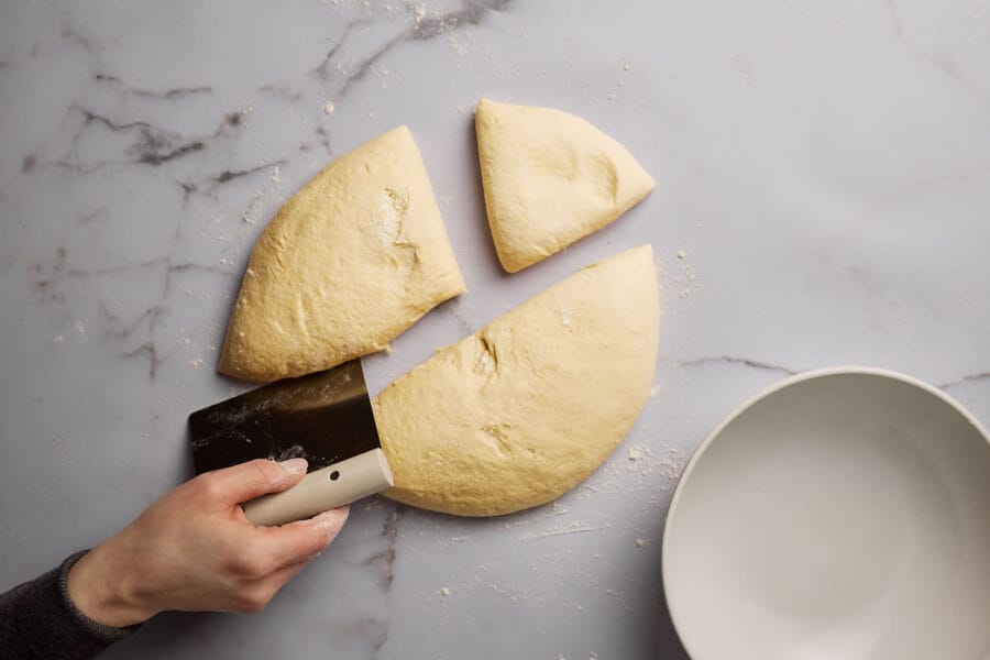 Hefeteig wird mit einer Teigkarte in Teigstücke geteilt.