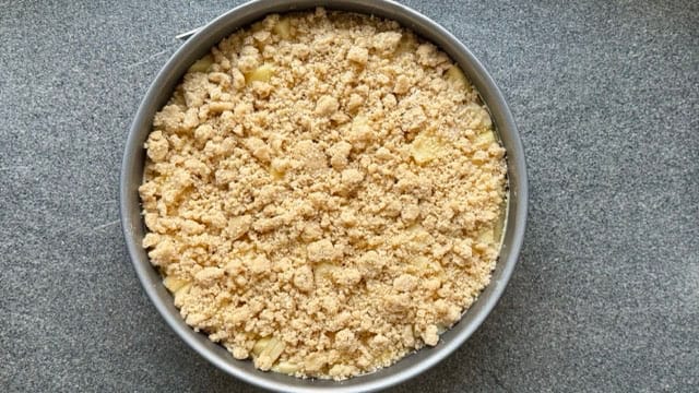 Streuselteig in die Springform geschichtet für Apfelkuchen.
