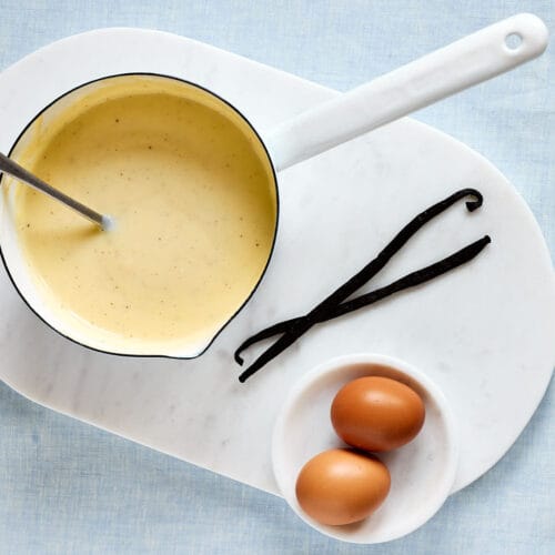 Selbstgemachte Vanillesoße wie von Oma – mit echter Vanille in einem Topf mit Vanilleschoten und Eiern daneben.