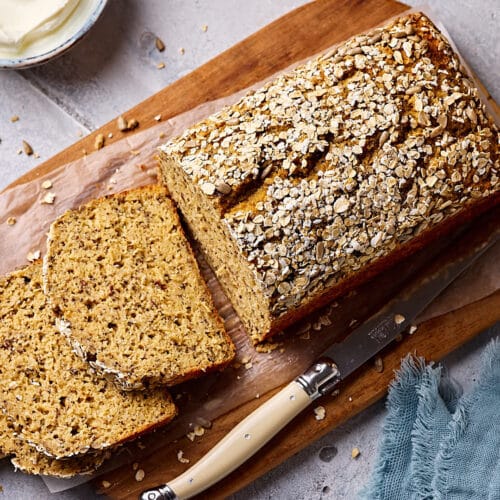 Schnelles Eiweißbrot mit Quark, aufgeschnitten auf einem Holzbrett mit Quark und Salz im Hintergrund.