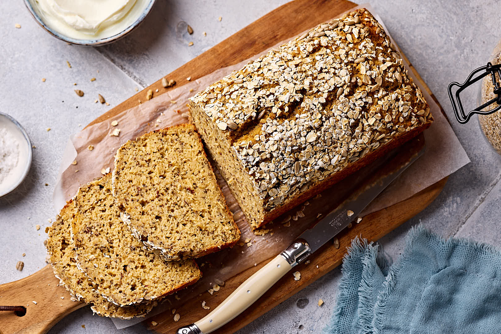 Schnelles Eiweißbrot mit Quark, aufgeschnitten auf einem Holzbrett mit Quark und Salz im Hintergrund.