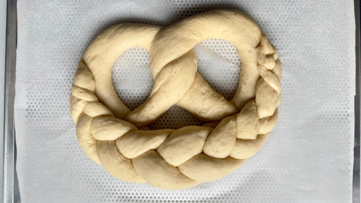 Fertige geformte Hefebrezel auf einem Backblech.