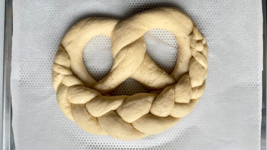Fertige geformte Hefebrezel auf einem Backblech.