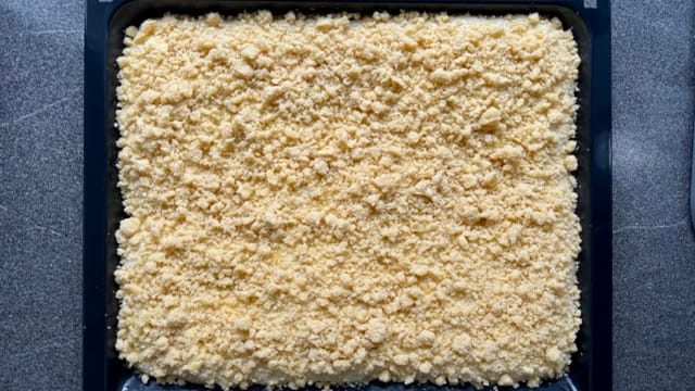 Streuselteig auf dem Hefeteig verteilt.