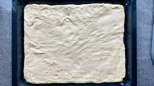 Hefeteig auf dem Backblech verteilt.