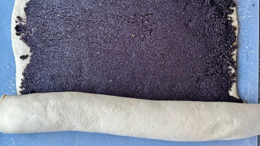 Gefüllten Hefeteig zu einer Rolle aufrollen.