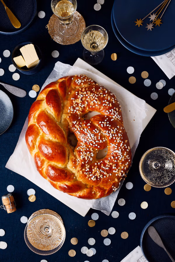 Neujahrsbrezel aus Hefeteig auf einem festlichen Tisch mit Sektgläsern und Konfetti.