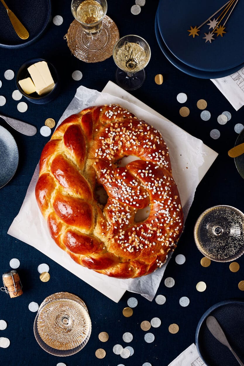 Neujahrsbrezel aus Hefeteig auf einem festlichen Tisch mit Sektgläsern und Konfetti.