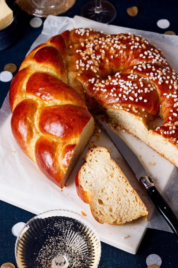 Neujahrsbrezel aus Hefeteig, aufgeschnitten mit luftiger Krume auf einem festlichen Tisch mit Sektgläsern und Konfetti.