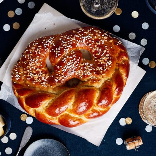 Neujahrsbrezel aus Hefeteig auf einem festlichen Tisch mit Sektgläsern und Konfetti.