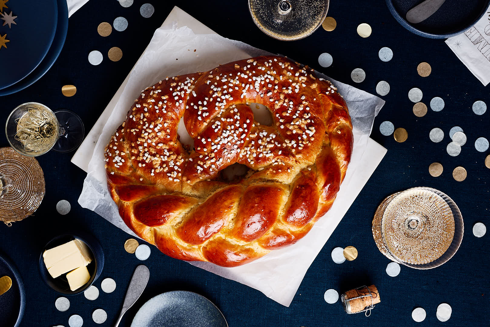 Neujahrsbrezel aus Hefeteig auf einem festlichen Tisch mit Sektgläsern und Konfetti.
