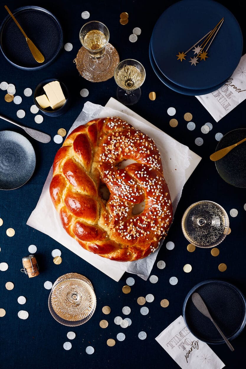 Neujahrsbrezel aus Hefeteig auf einem festlichen Tisch mit Sektgläsern und Konfetti.