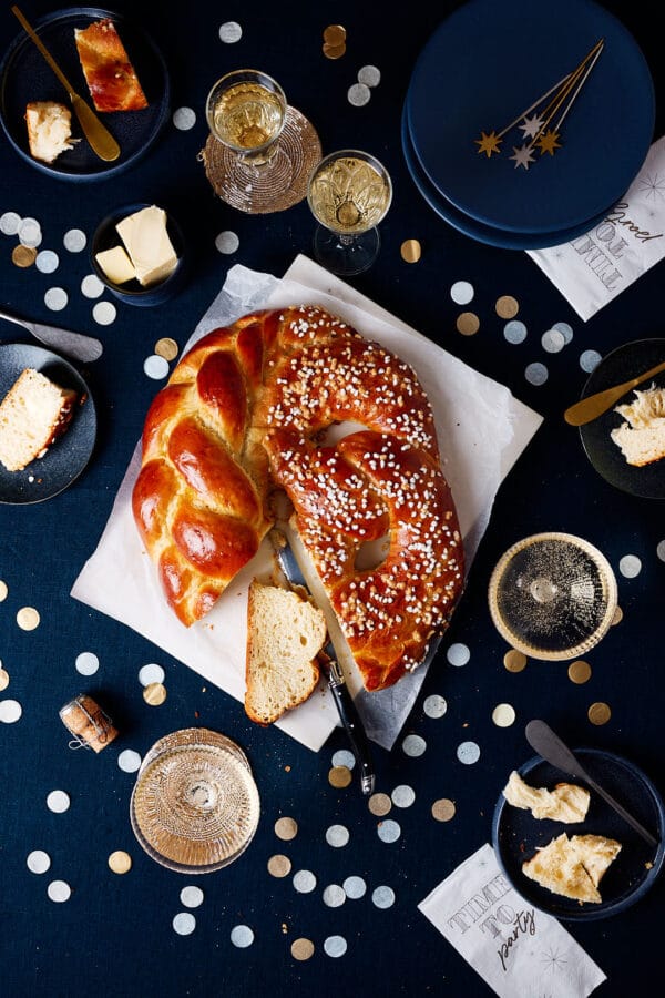 Neujahrsbrezel aus Hefeteig auf einem festlichen Tisch mit Sektgläsern und Konfetti.