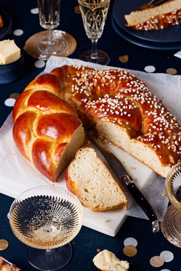 Neujahrsbrezel aus Hefeteig, aufgeschnitten mit luftiger Krume auf einem festlichen Tisch mit Sektgläsern und Konfetti.