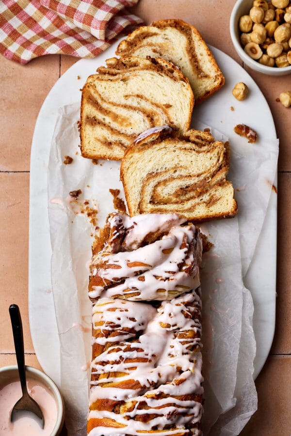 Saftiger Nusszopf auf einem Marmortablett mit Puderzucker-Guss.