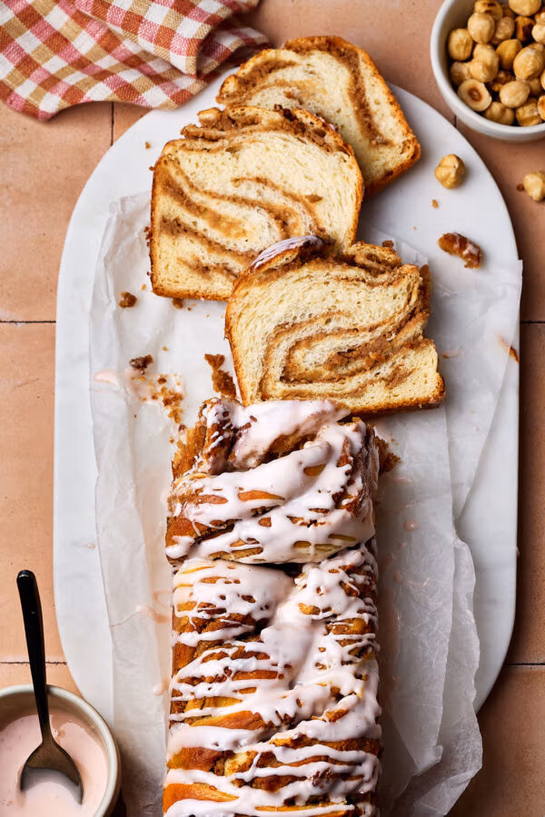 Saftiger Nusszopf auf einem Marmortablett mit Puderzucker-Guss.