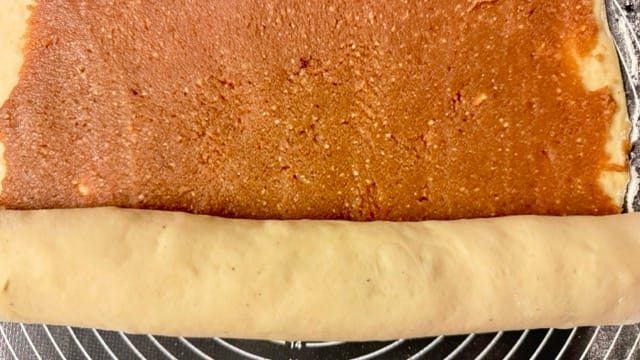 Nusszopfteig mit Nussfüllung aufrollen.