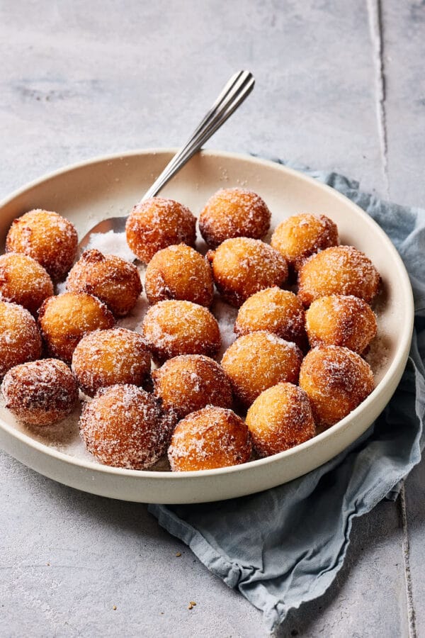 Luftige Quarkbällchen mit Zuckerkruste in einer großen Schale mit Zucker.