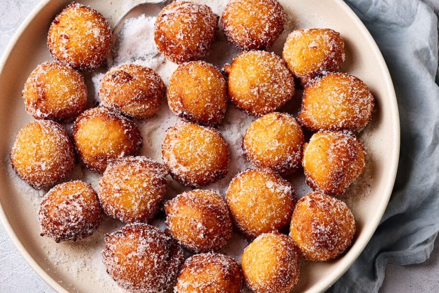 Luftige Quarkbällchen mit Zuckerkruste in einer großen Schale mit Zucker.