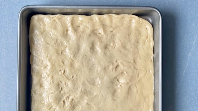 Hefeteig für Omas Butterkuchen auf dem Backblech verteilt.