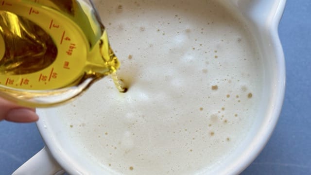 Aufgeschlagene Eier in einer Schüssel für Saatenbrot ohne Mehl ud Hefe mit Olivenöl.