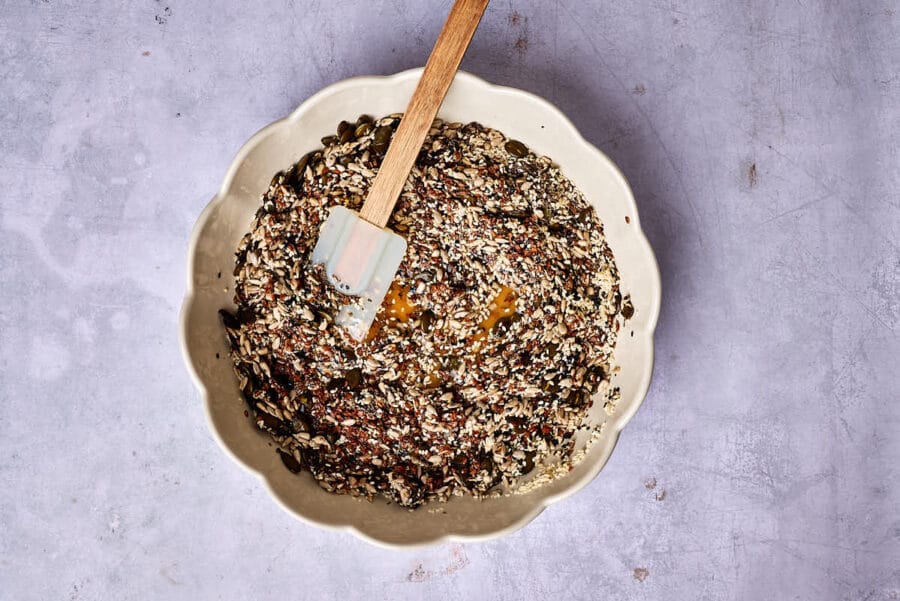 Saaten, Gewürze und Wasser werden in einer Schüssel für Saatencracker ohne Mehl vermengt.