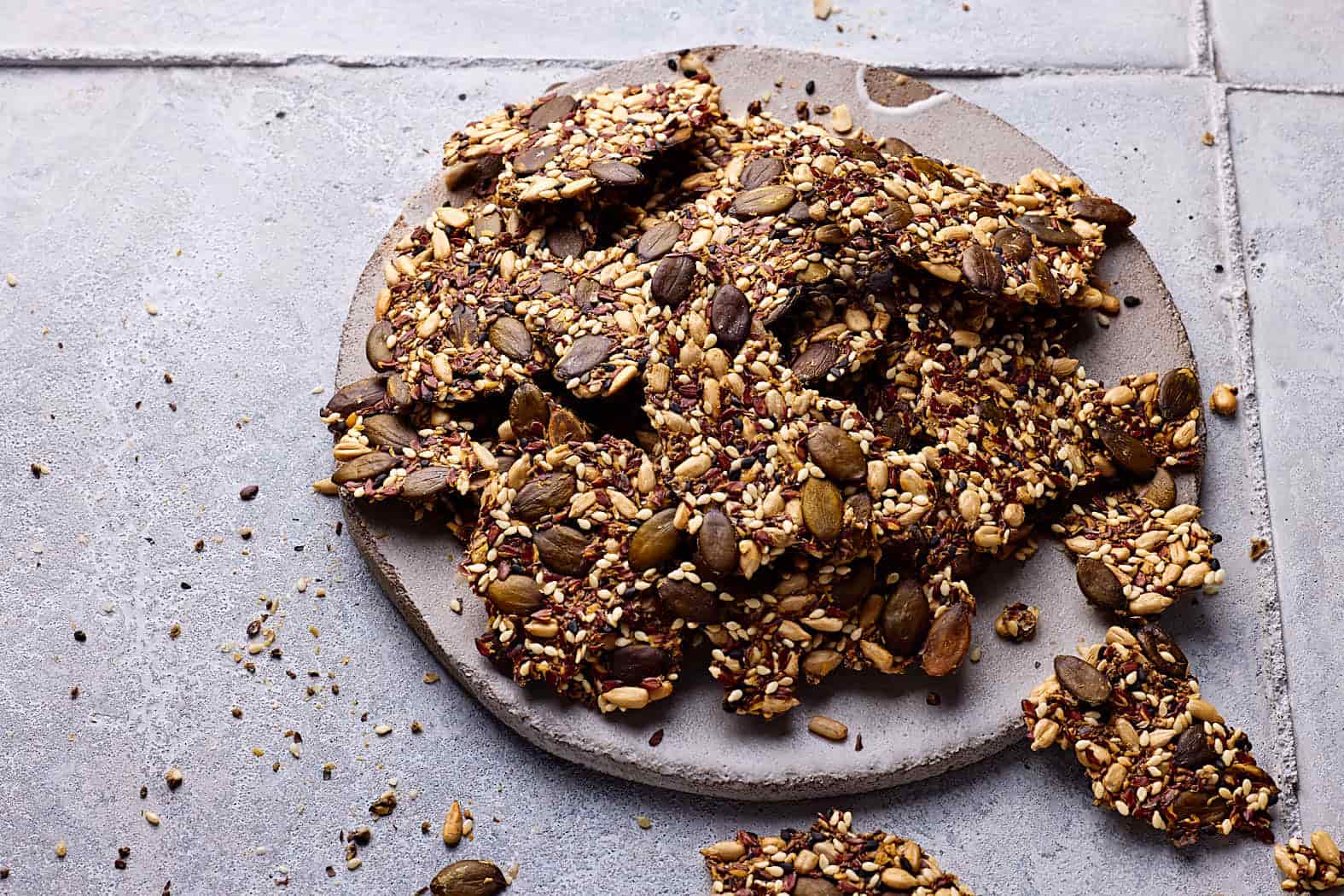 Saatencracker ohne Mehl auf einer Steingutplatte mit Körner-Crackern drumherum.