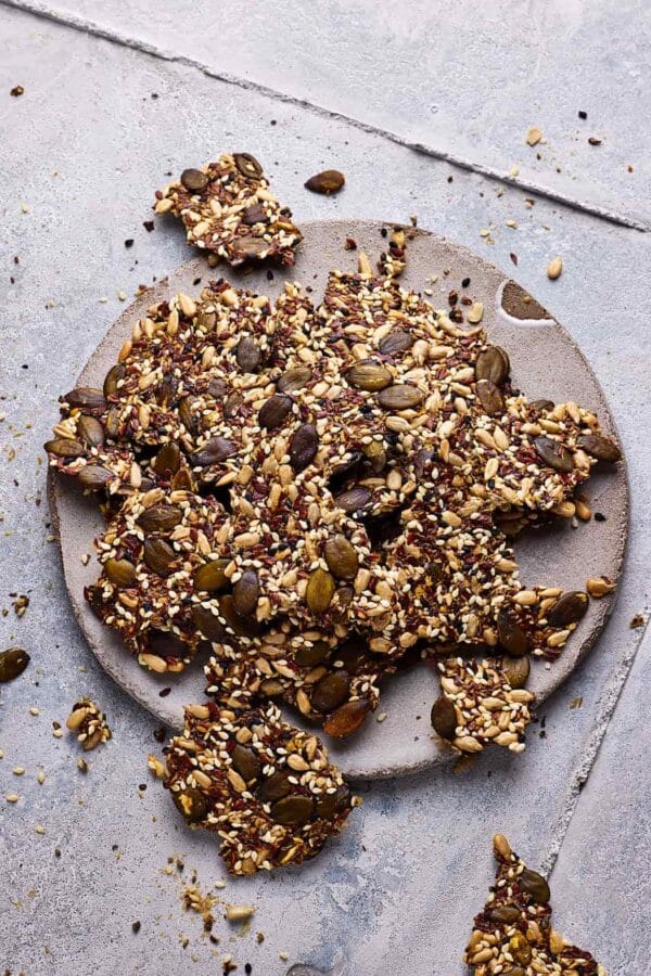 Saatencracker ohne Mehl auf einer Steingutplatte mit Körner-Crackern drumherum.