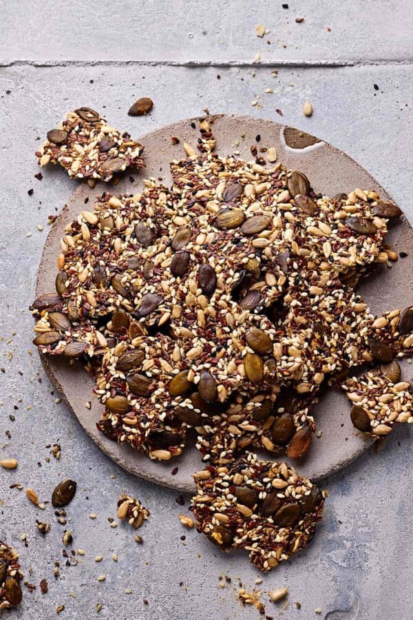 Saatencracker ohne Mehl auf einer Steingutplatte mit Körner-Crackern drumherum.