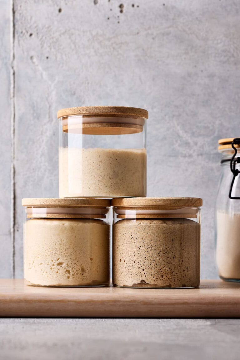 Sauerteig aufbewahren, Roggensauerteig, Weizensauerteig und Lievito Madre in Gläsern mit einem Holzdeckel.