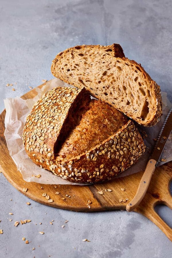 Dinkelbrot backen: aufgeschnittenes Dinkelbrot mit goldbrauner Kruste und lockerer Krume auf einem Holzbrett.