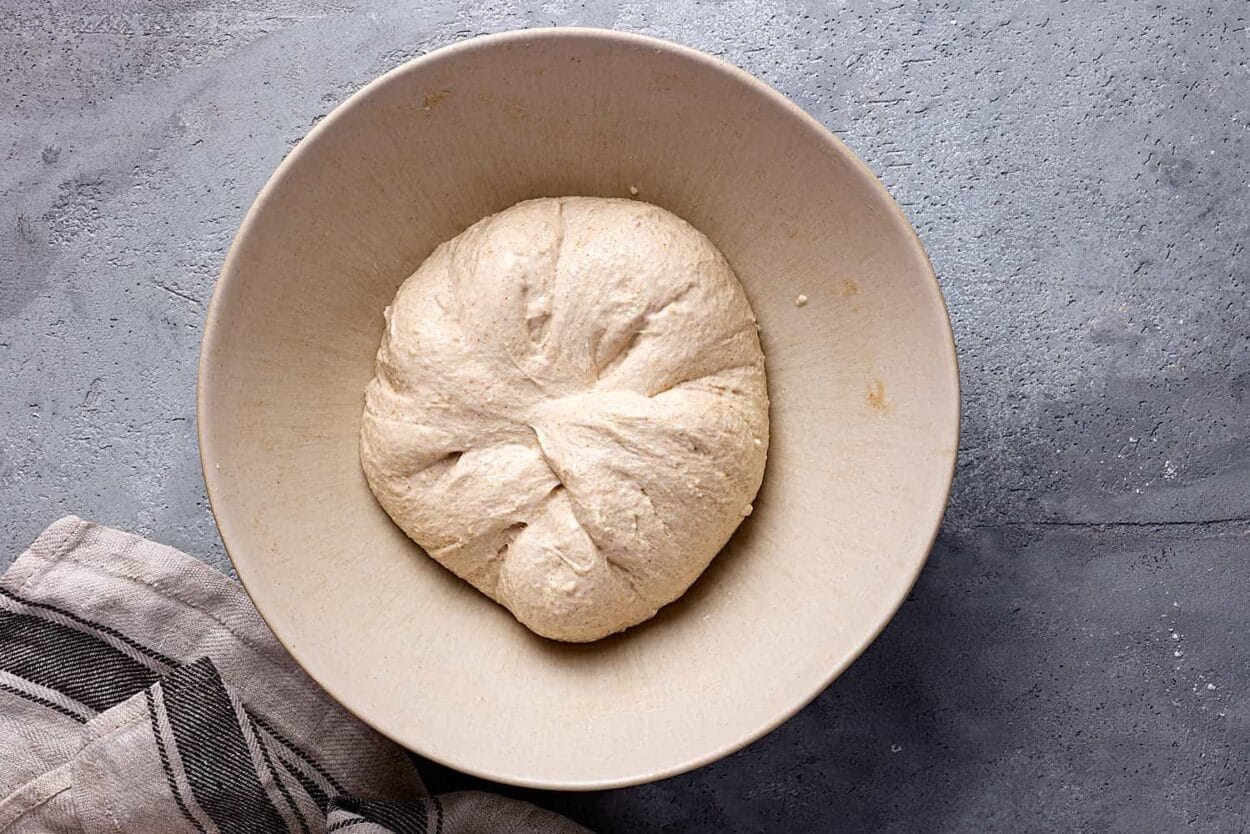 Fertig gedehnt und gefalteter Teig für Sauerteigbrot in einer Keramikschüssel. 
