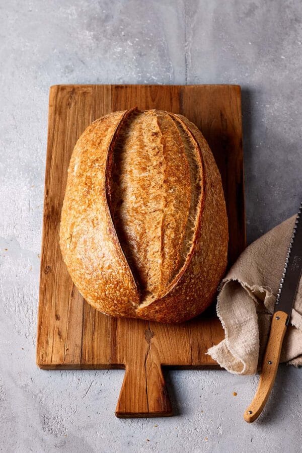 Einfaches Sauerteigbrot mit Weizensauerteig, mit goldbrauner Kruste auf einem Holzbrett. 